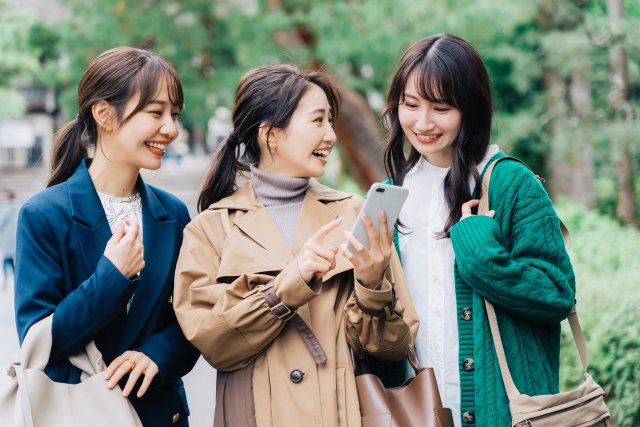 スマートフォンを見ながら出かける3人の女性