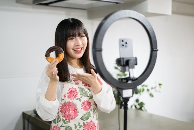 スマートフォンとリングライトで撮影する女性